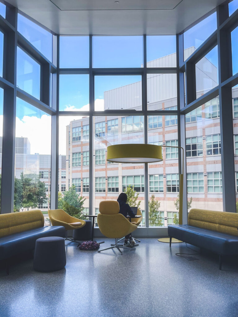 A student studies seated in a large bay window area at the Biological Sciences Building.